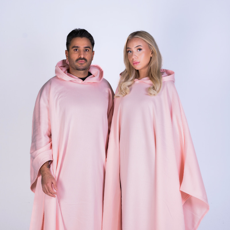 Two people wearing a soft pink Hoodly hoodie blanket