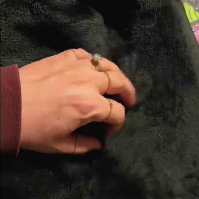 Hand pressing into the soft black fleece back of the blanket