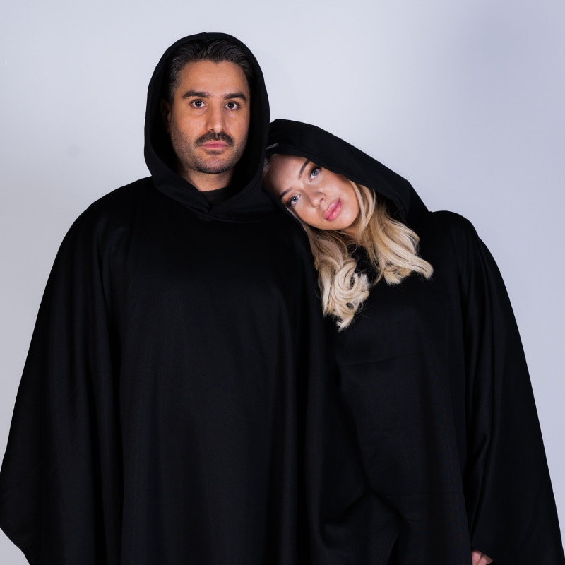 Two people wearing black Hoodly hoodie blankets